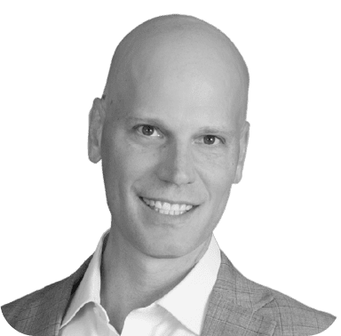 Portrait en noir et blanc d'un homme chauve souriant, vêtu d'un costume d'affaires.